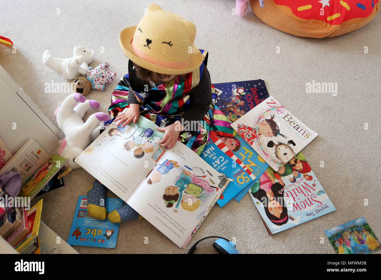 Une jeune fille lisant des livres dans sa chambre vêtue de vêtements colorés cool à Londres, au Royaume-Uni. Banque D'Images