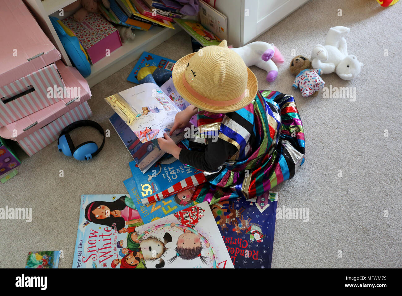 Une jeune fille lisant des livres dans sa chambre vêtue de vêtements colorés cool à Londres, au Royaume-Uni. Banque D'Images