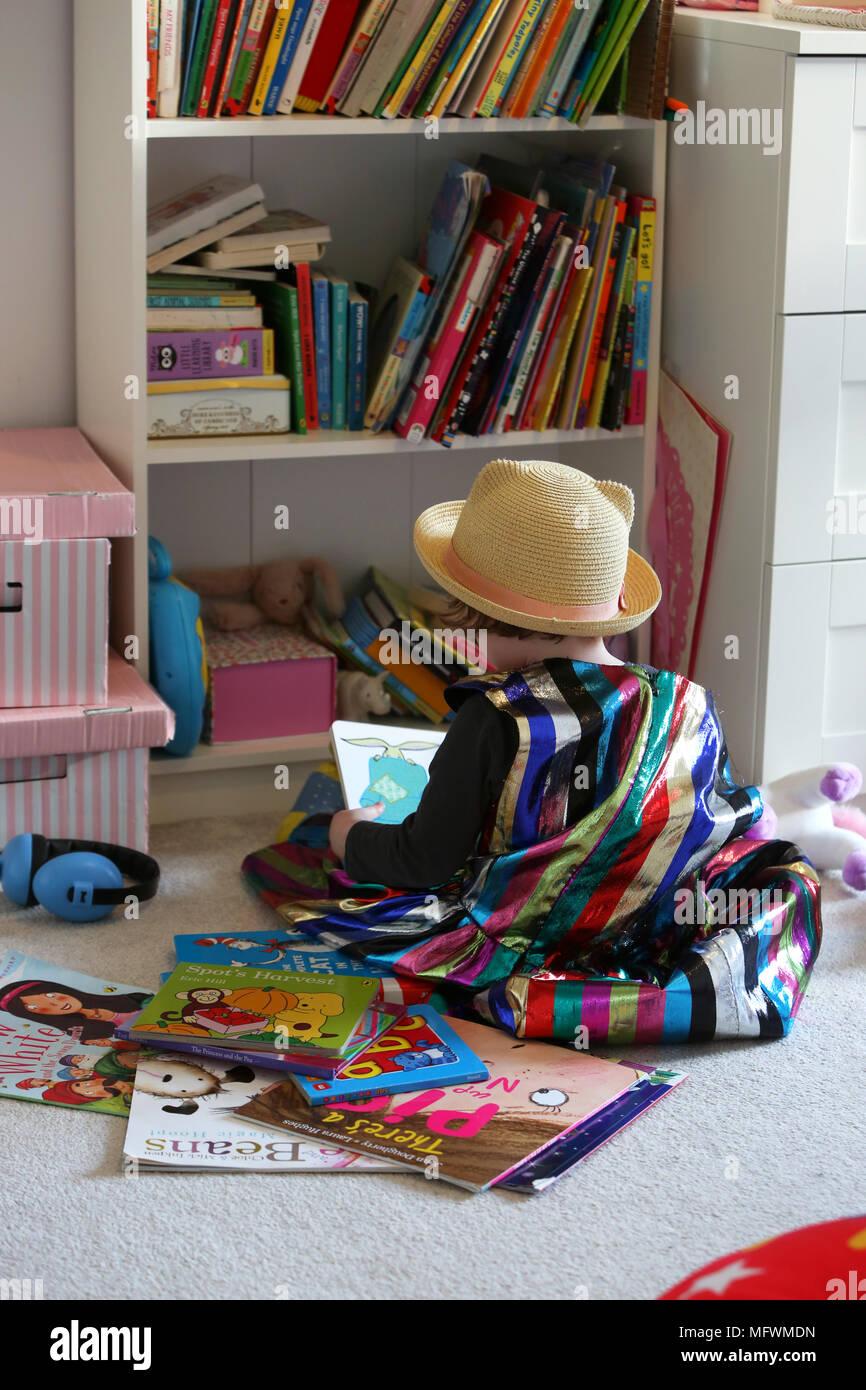 Une jeune fille lisant des livres dans sa chambre vêtue de vêtements colorés cool à Londres, au Royaume-Uni. Banque D'Images