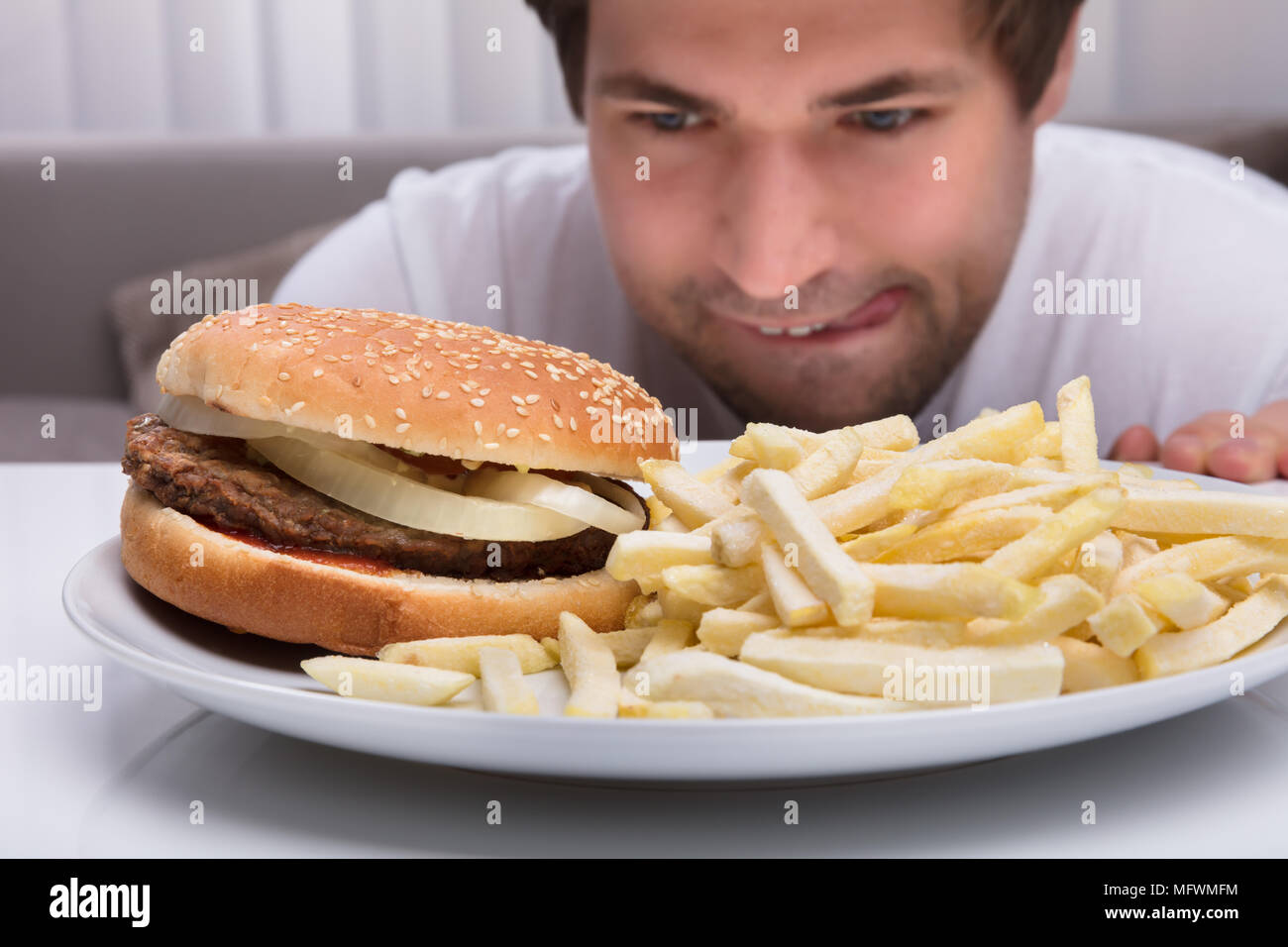 Close-up of a Young Man Looking At burger et frites On Plate Banque D'Images