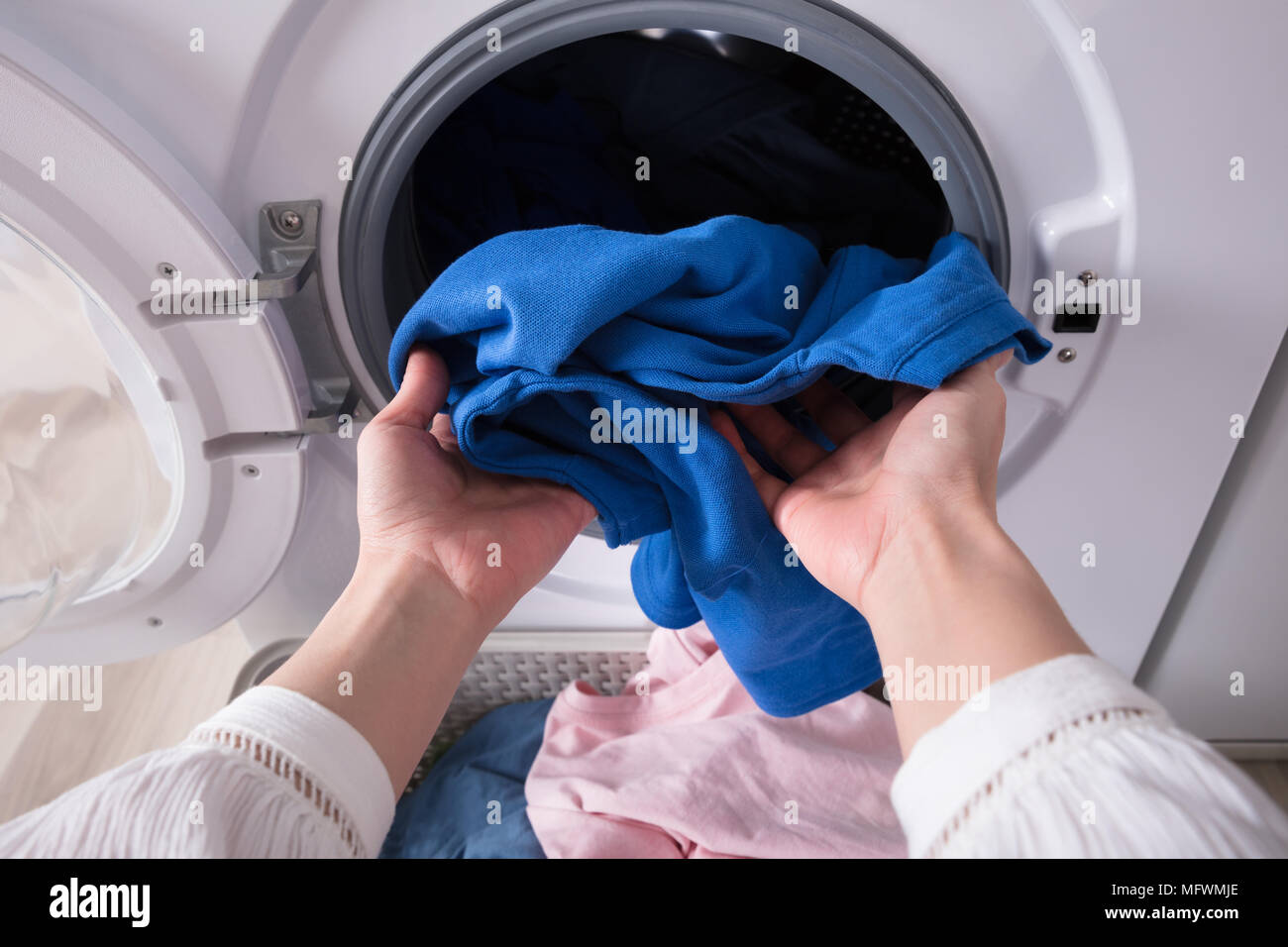 Close-up of a Woman's Hand Putting Sale Chiffon bleu en lave-linge Banque D'Images