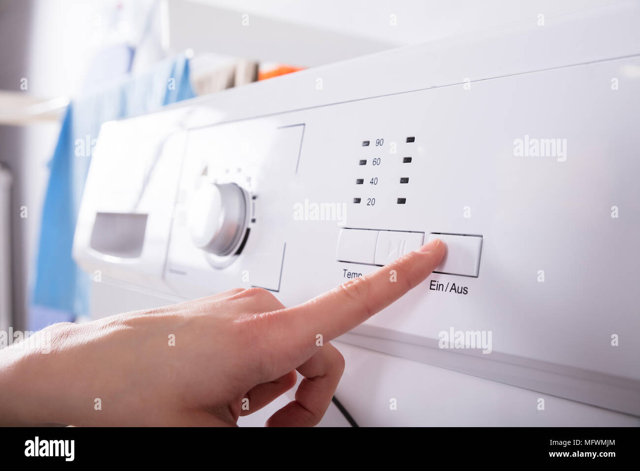 Close-up of a person's doigt appuyant sur le bouton de la machine à laver Banque D'Images