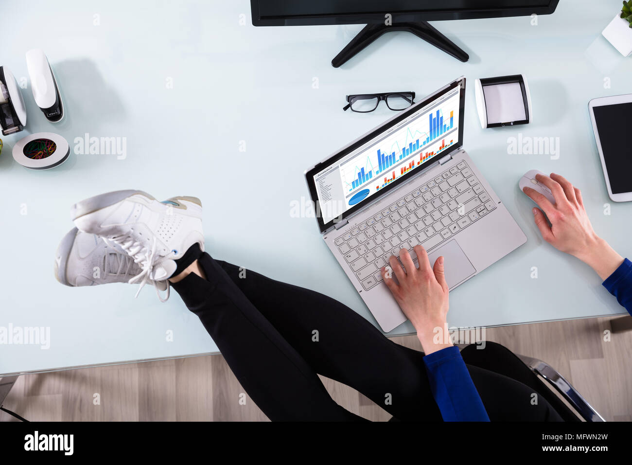 Portrait de l'homme d'affaires, l'analyse graphique sur ordinateur portable avec jambes croisées sur le bureau Banque D'Images