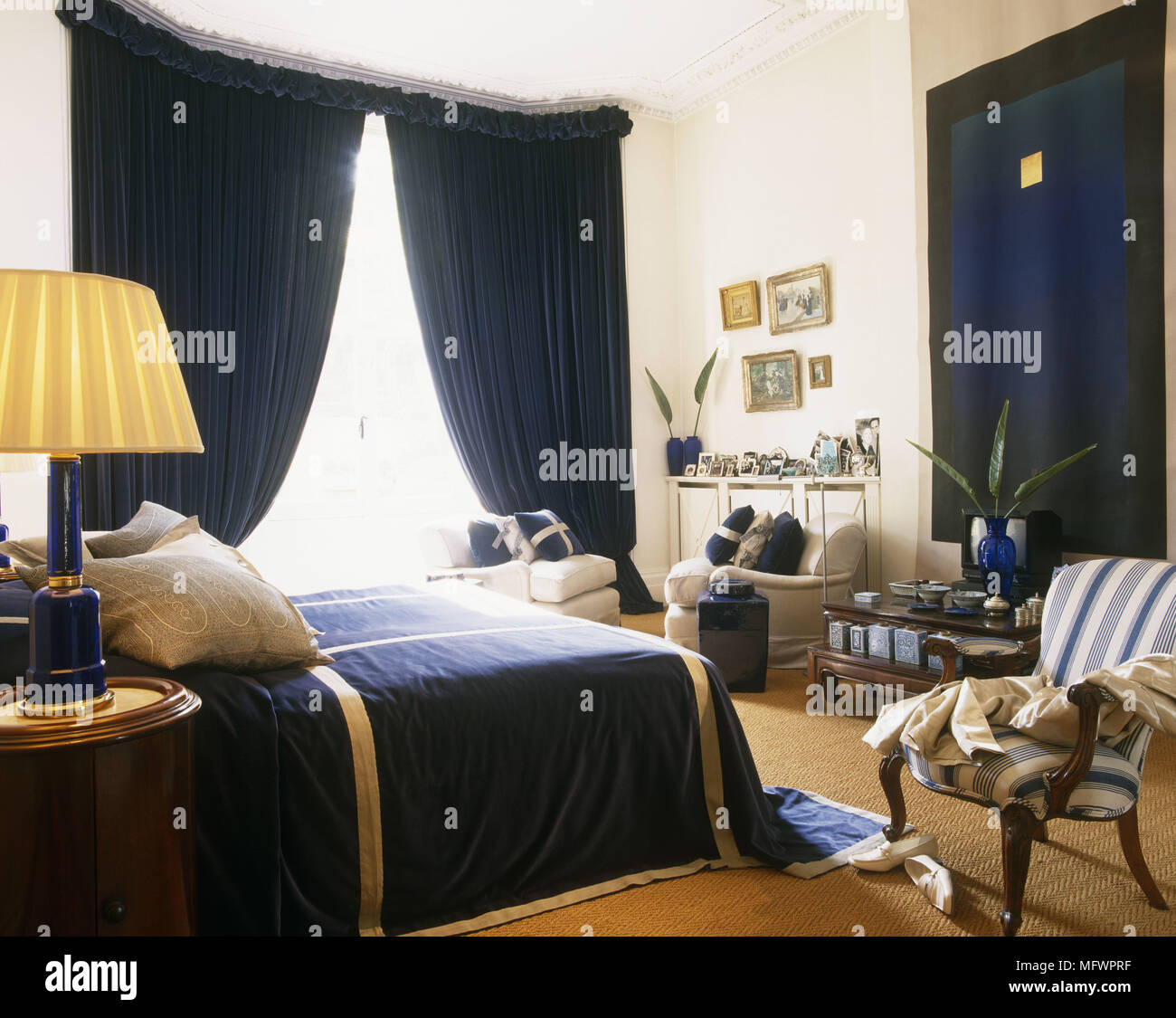 Chambre avec des rideaux bleus face à lit double avec coussins et table lamp Banque D'Images