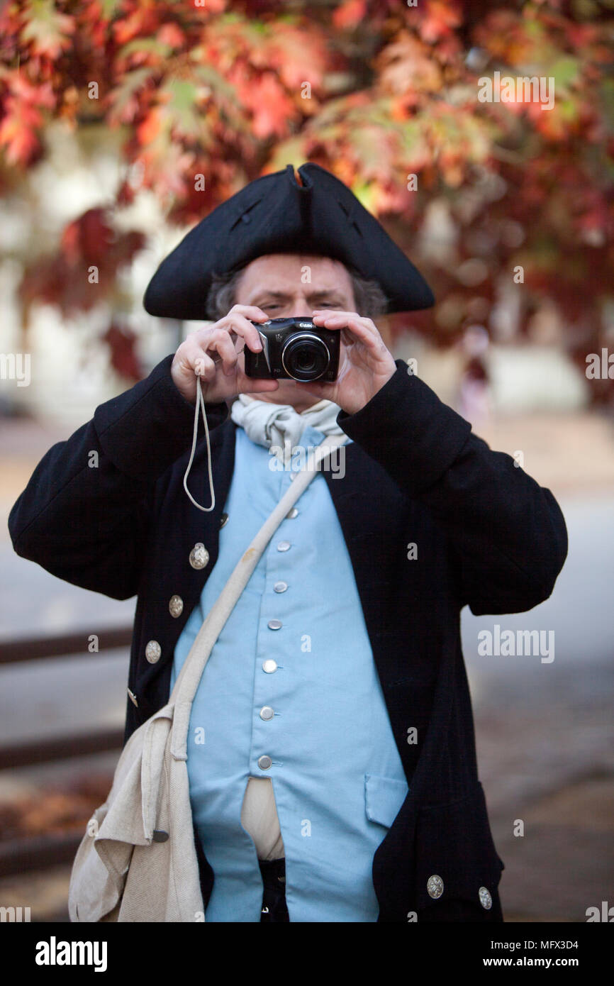 Une photo d'un acteur en costume 18 siècle à l'aide d'un 21e siècle caméra numérique en Colonial Williamsburg en Virginie Banque D'Images
