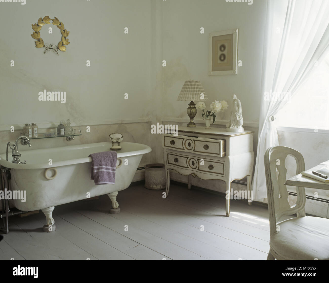 Un pays salle de bains avec une baignoire blanc rustique commode bureau et une chaise sur un plancher en bois. Banque D'Images