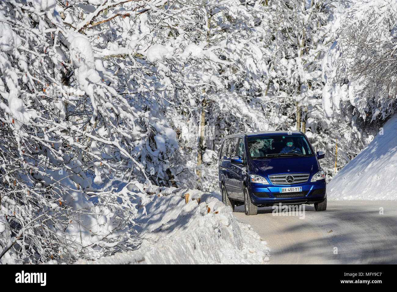 Un transfert minibus durs le long d'une route couverte de neige dans la station alpine de Courchevel. Banque D'Images