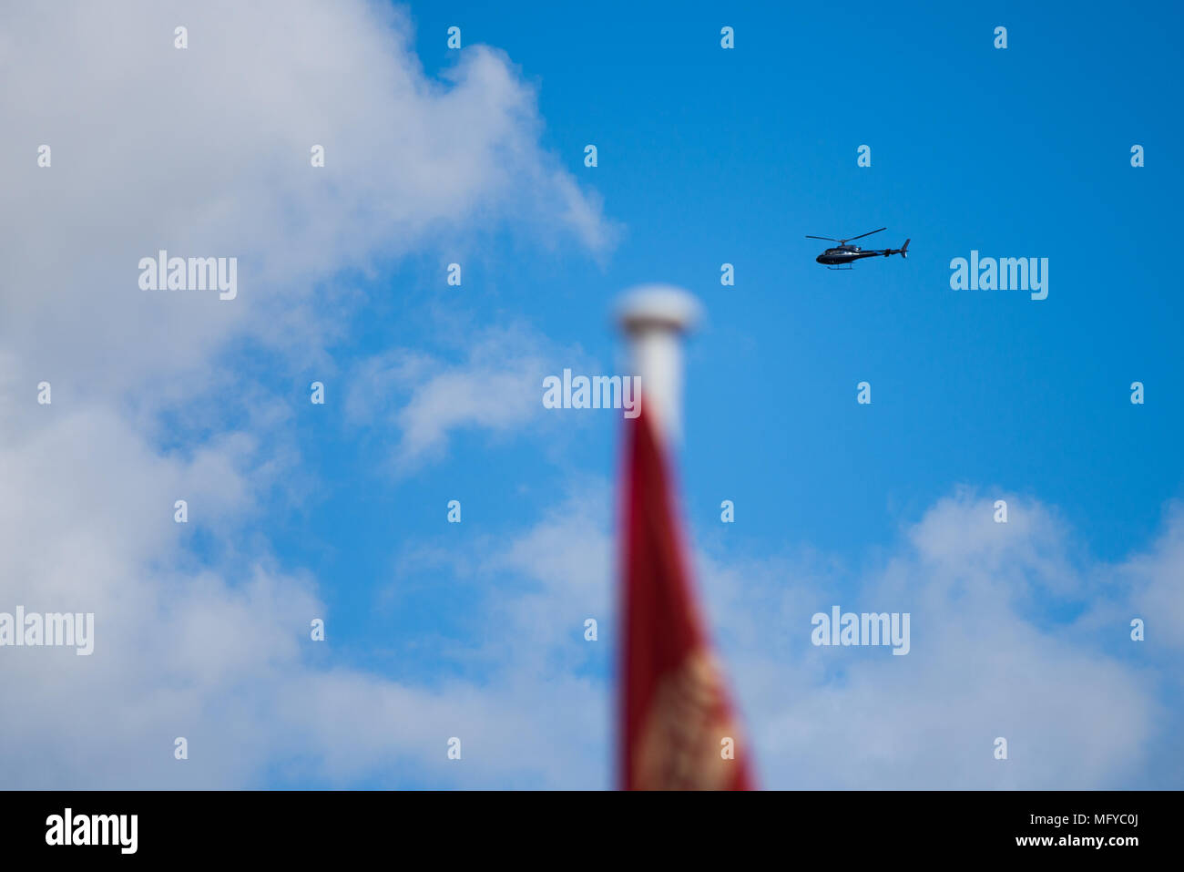 Hélicoptère vole dans le bleu ciel nuageux avec drapeau flou en premier plan Banque D'Images