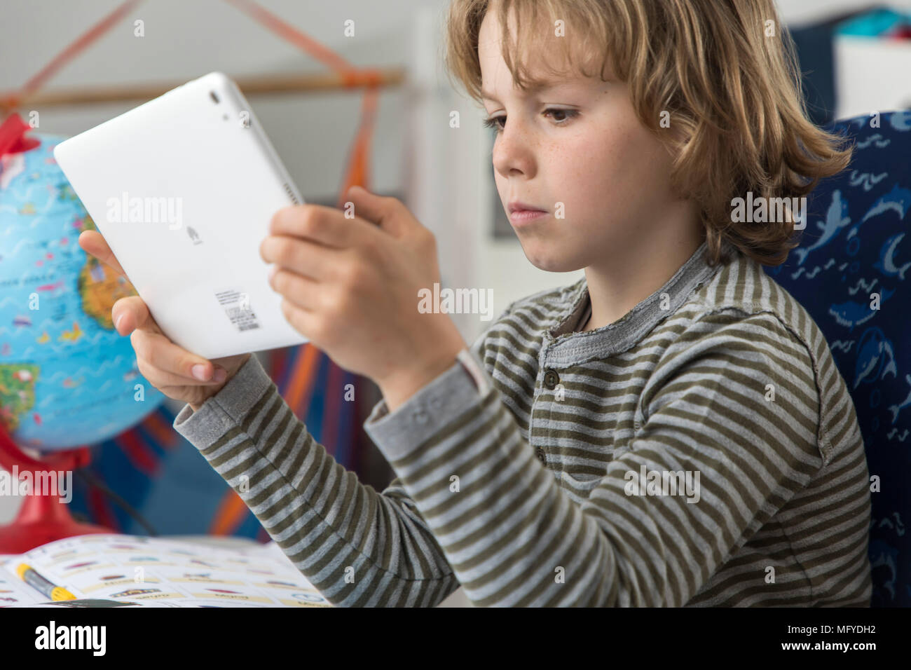 Garçon, école primaire, 8 ans, apprend à l'école à la maison, devoirs, n'utilise un ordinateur tablette pour l'apprentissage, Banque D'Images
