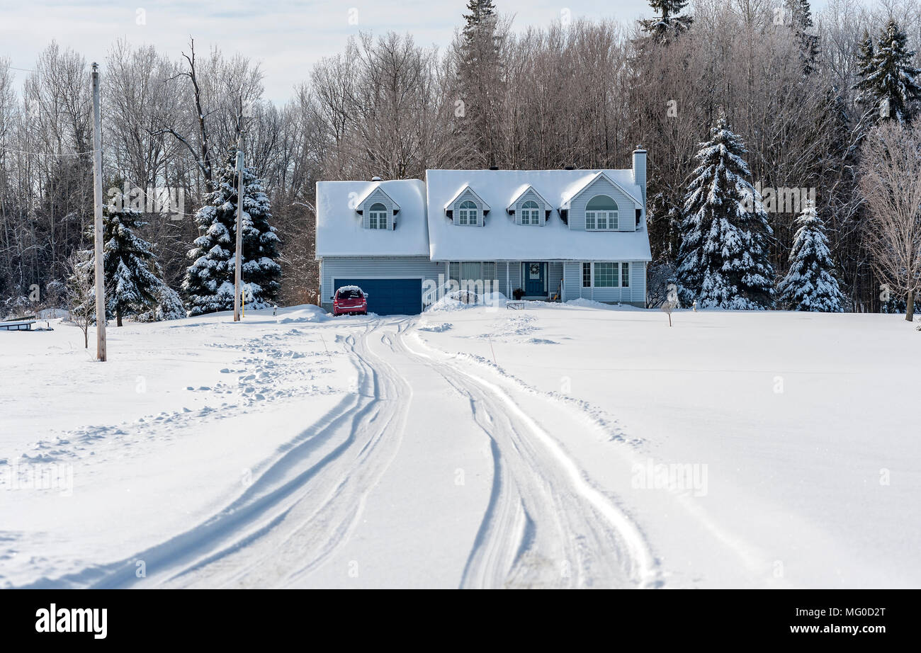 Allée couverte de neige longue avec traces de mener à une maison blanche, et de la forêt. Banque D'Images