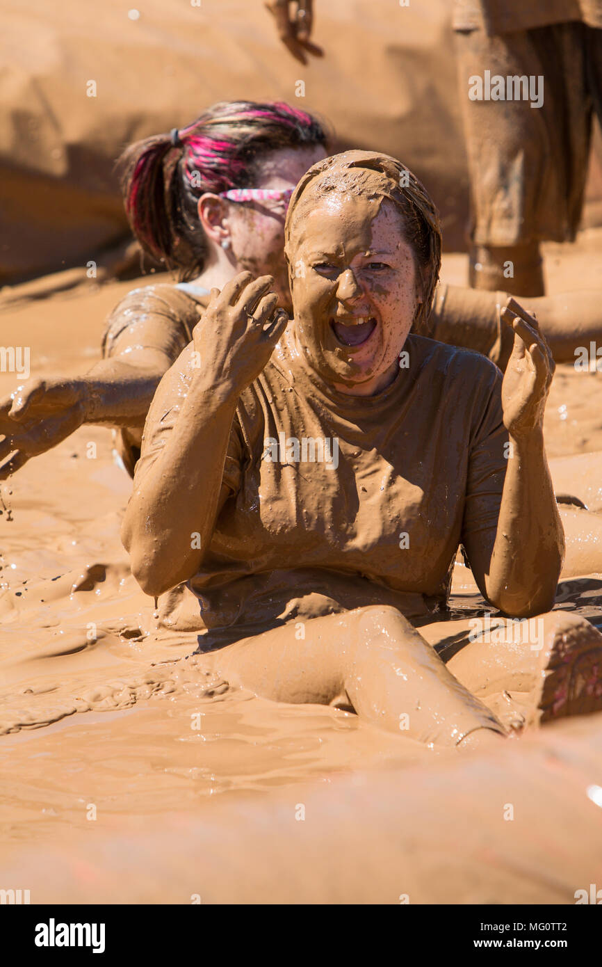 Une femme couverte de boue rires après glisser dans une fosse d'eau boueuse à la sale fille Mud Run course à obstacles event le 23 avril 2016 à Hampton, GA. Banque D'Images