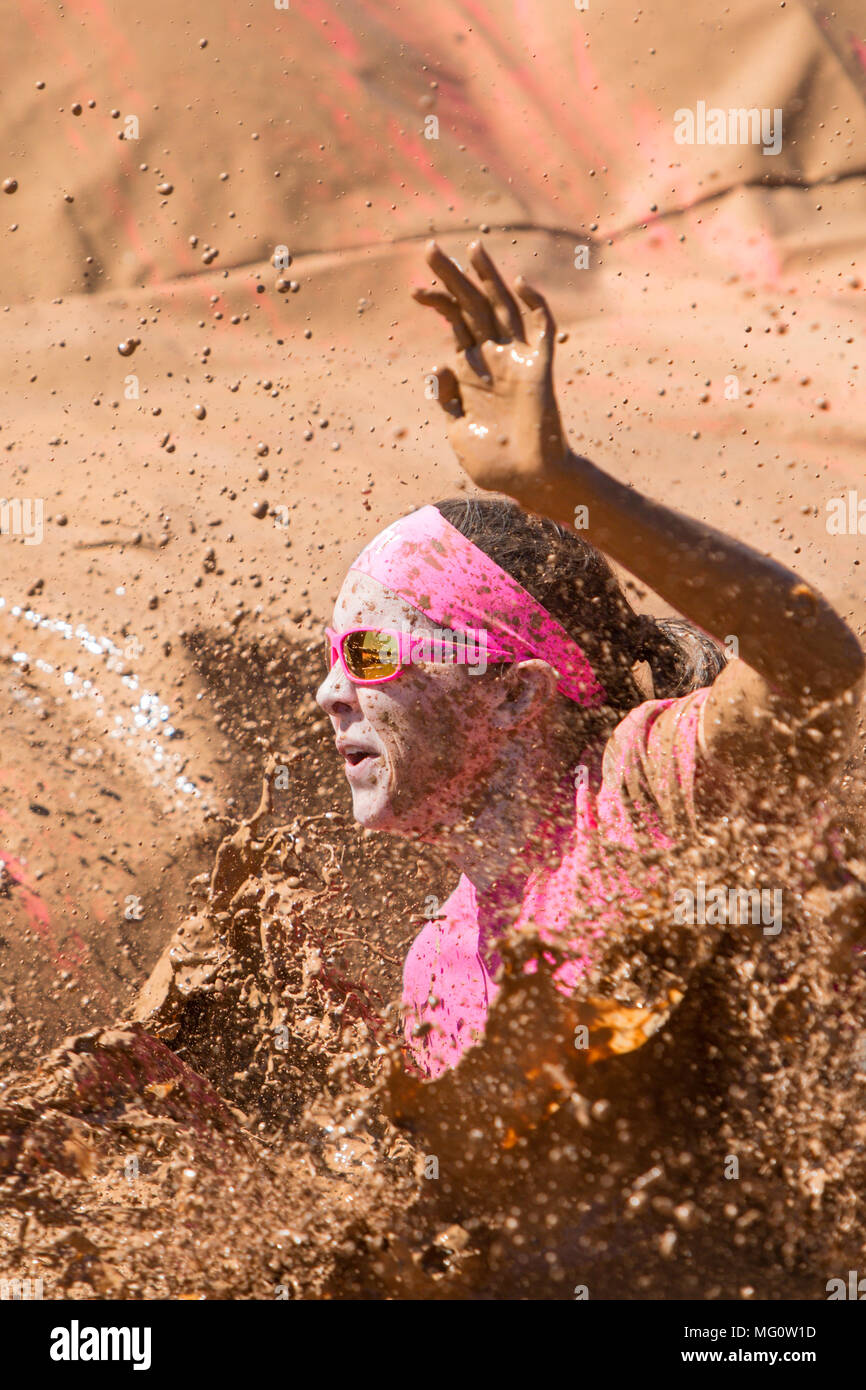 Les éclaboussures de l'eau boueuse d'une femme comme elle les terres dans une boue à la sale fille Mud Run course à obstacles event le 23 avril 2016 à Hampton, GA. Banque D'Images
