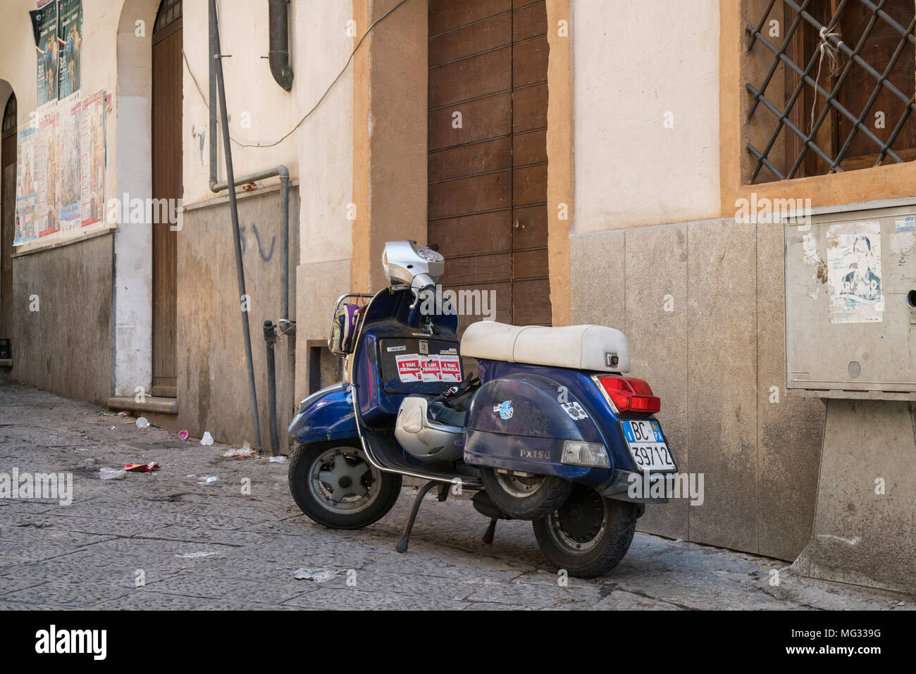 Un ancien bleu Vespa PX150 scooter garé dans une rue de Palerme, Sicile, Italie. La confiance à la propriétaire a laissé les clefs dans le contact ! Banque D'Images