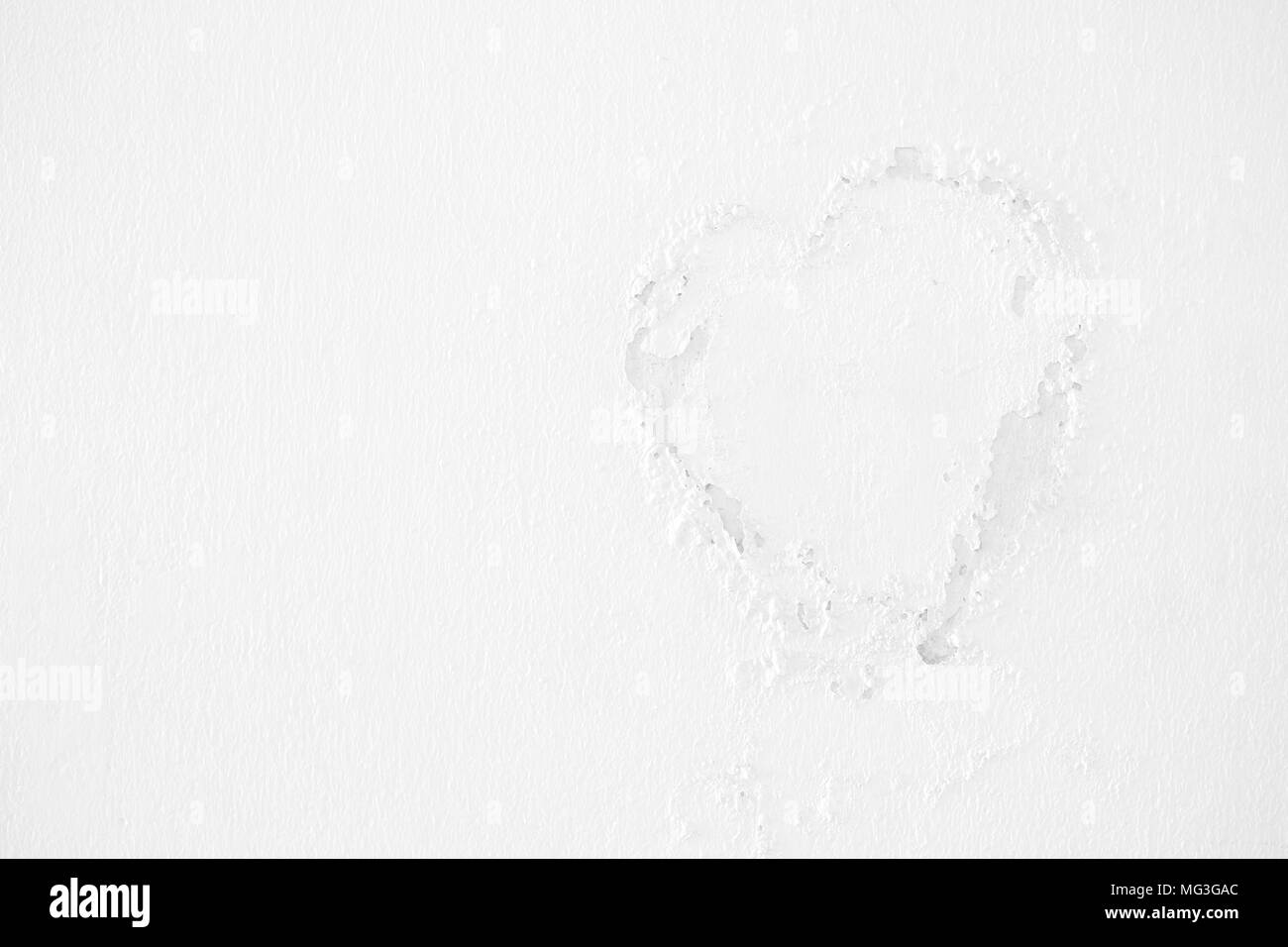 L'écaillage de la peinture blanche en forme de coeur sur le mur de béton. Banque D'Images