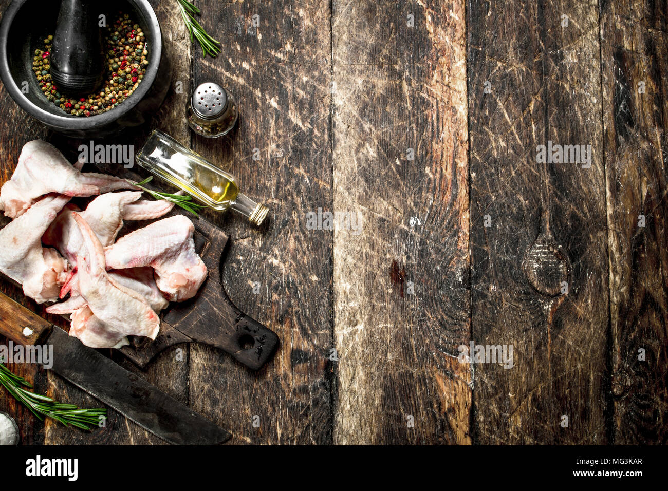 Ailes de poulet crues avec épices et herbes. Sur une table en bois. Banque D'Images