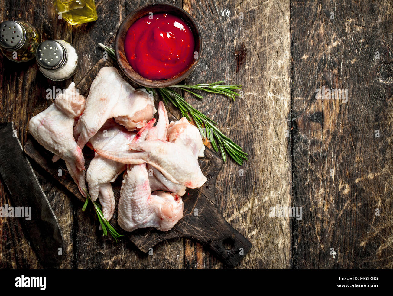 Ailes de poulet crues avec une sauce tomate et fines herbes. Sur une table en bois. Banque D'Images
