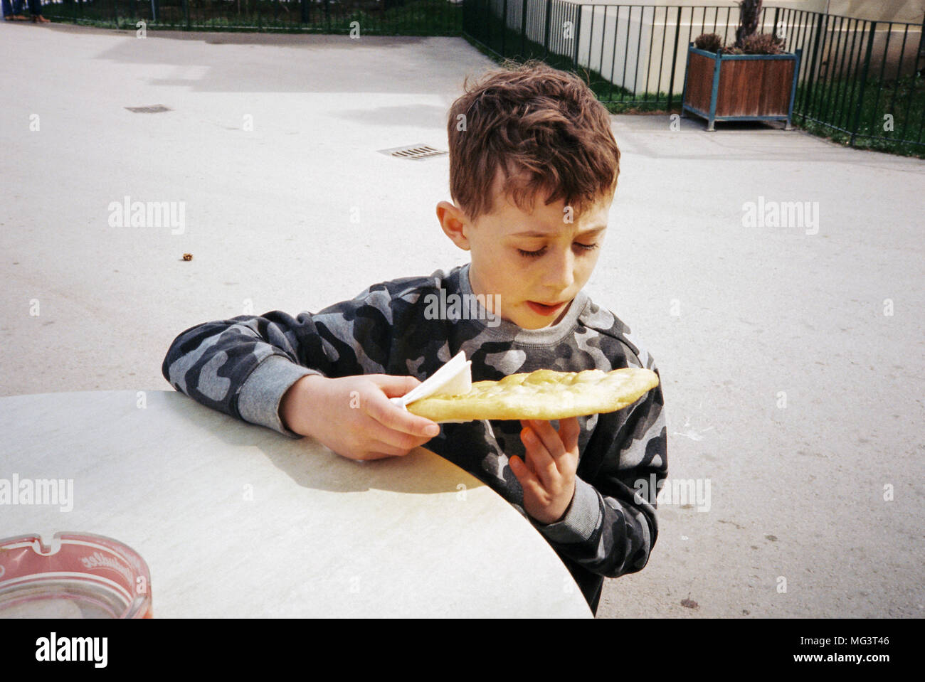 Garçon de huit ans de manger un Lángos, un pain plat frit.Zoo de Schönbrunn, Maxingstraße, Vienne, Autriche, Europe. Banque D'Images