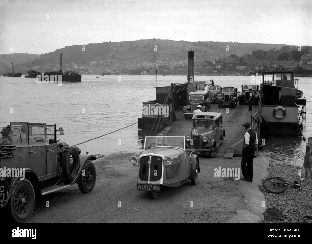 Une voiture à trois roues Raleigh Safety t conduit un ferry à Devon dans les années 1930, entourée de voitures anciennes Banque D'Images