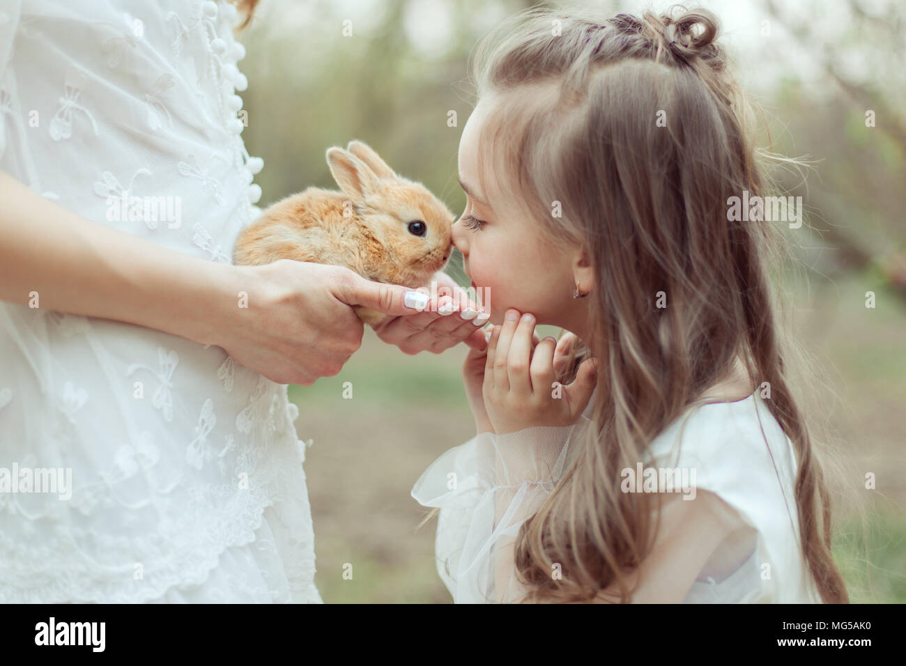 Maman est titulaire d'un petit lapin dans ses mains. Fille embrassant le lapin. Banque D'Images