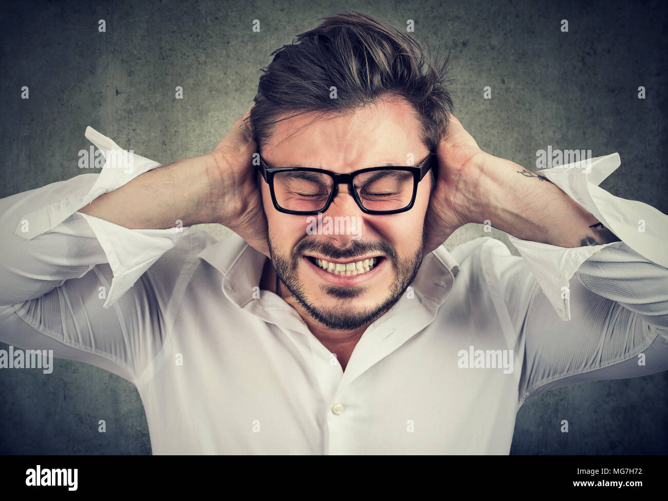 Fronçant barbu dans les verres couvrant les oreilles de l'hystérie et le stress. Ayant Banque D'Images