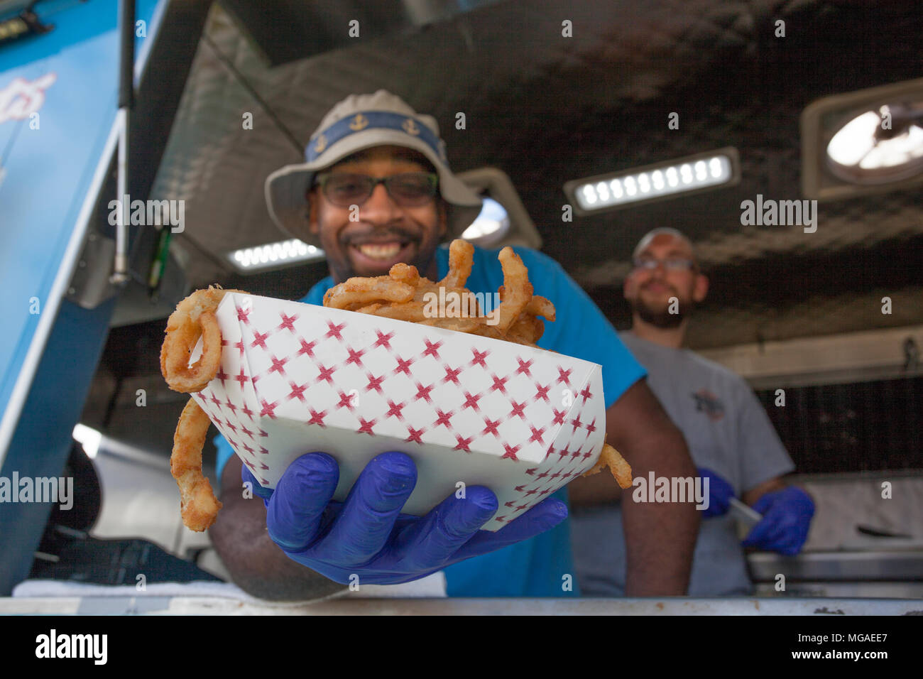 Afro-américain propriétaire de petite entreprise dans son camion alimentaire avec un panier plein d'oignon frit Banque D'Images
