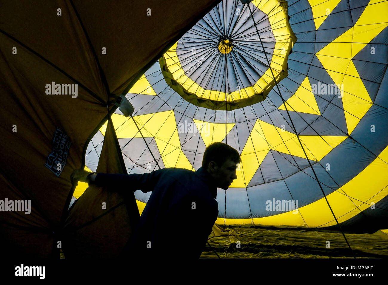 Silhouette d'un homme d'équipage à l'intérieur d'une montgolfière gonflage rétroéclairé Banque D'Images