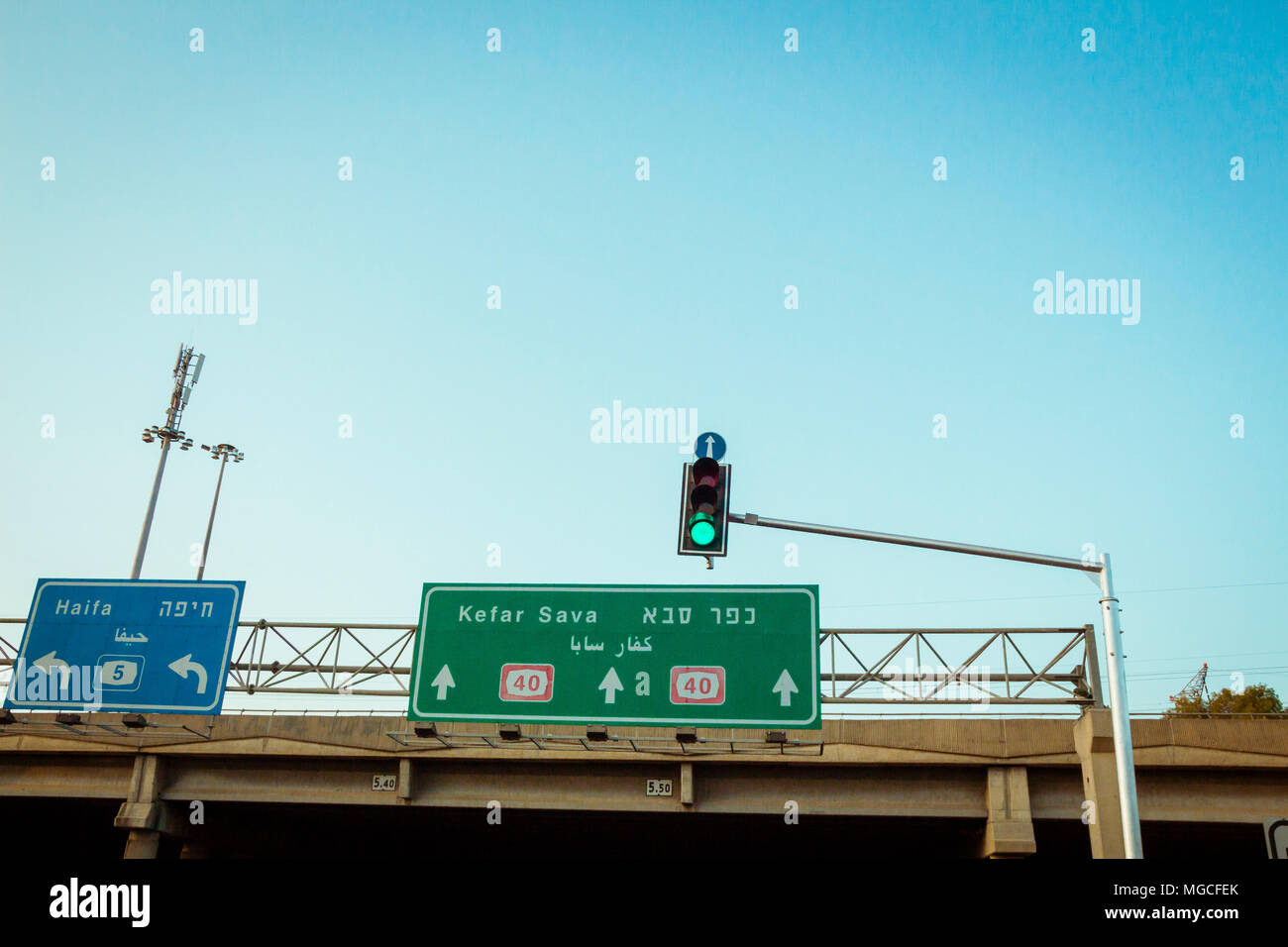 Feu vert à l'intersection en Israël. Les panneaux d'accroché sur pont en béton. L'un de diriger la circulation à Haïfa et l'autre à Kfar Banque D'Images