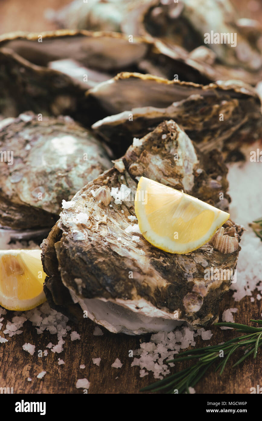 Oyster shell ouvert avec le citron et le sel sur une planche en bois Banque D'Images