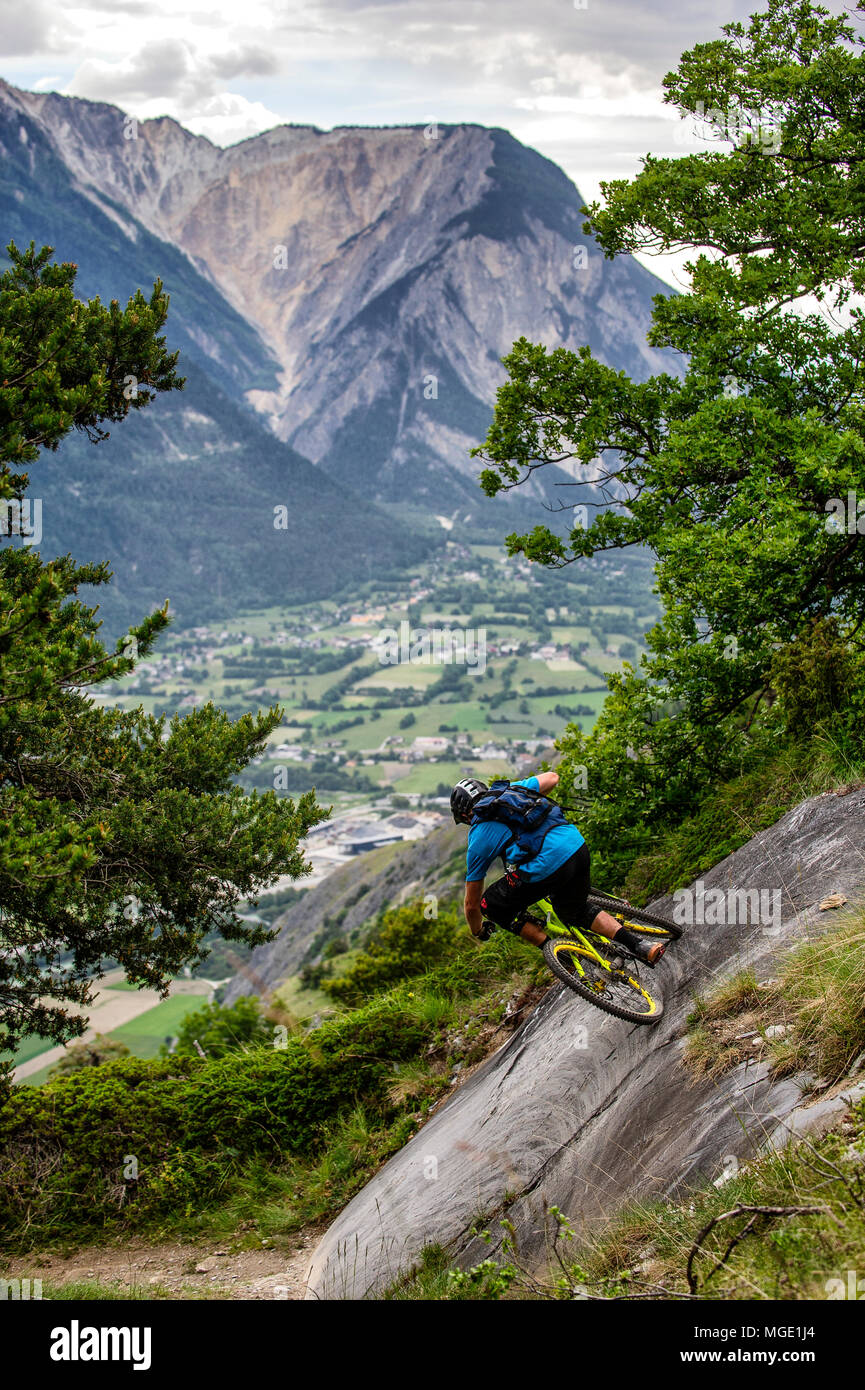 Un homme monte un vtt haut au-dessus de la vallée, près des villes de Gampel et Jeizinen dans le Valais Suisse. Banque D'Images