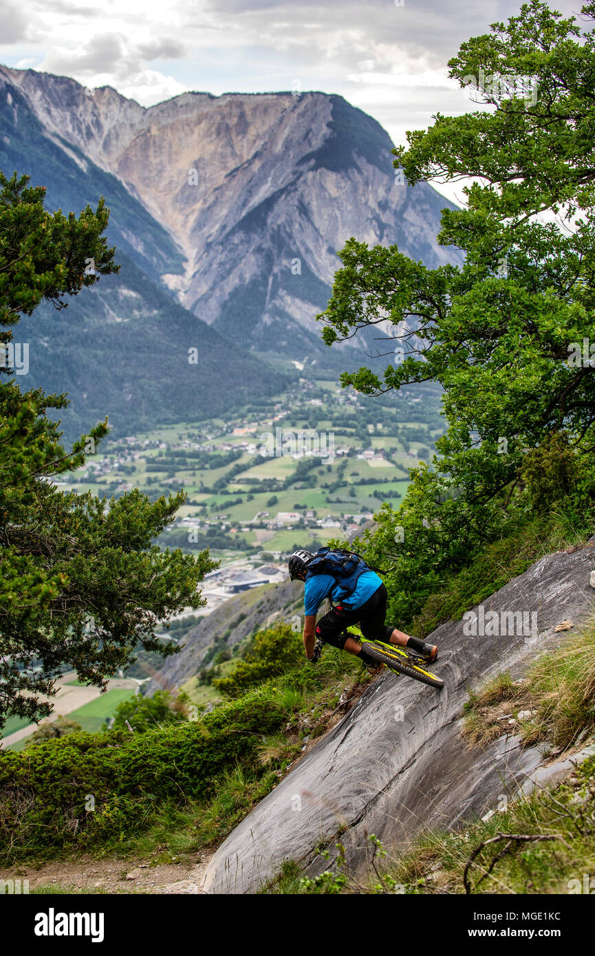 Un homme monte un vtt haut au-dessus de la vallée, près des villes de Gampel et Jeizinen dans le Valais Suisse. Banque D'Images