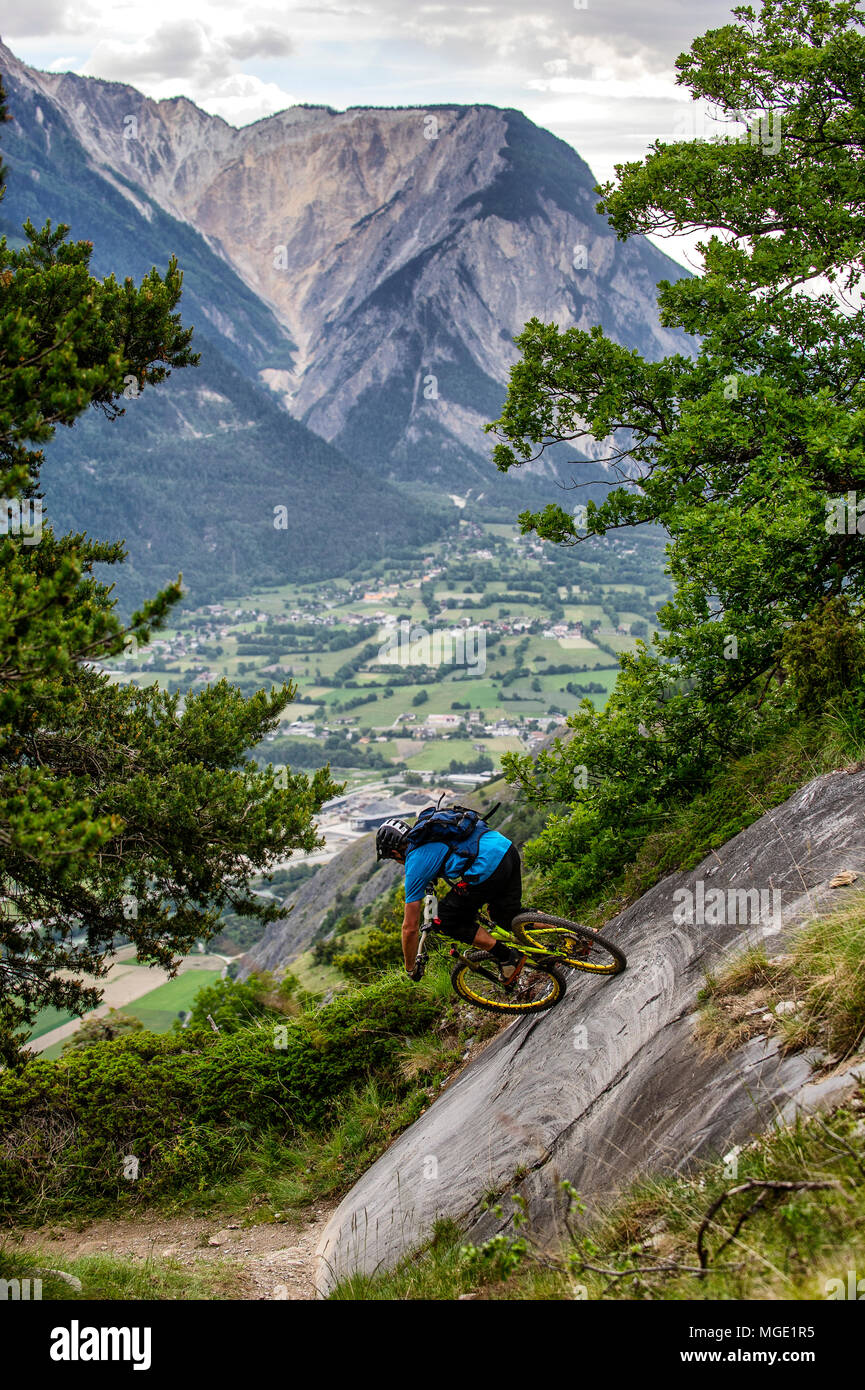 Un homme monte un vtt haut au-dessus de la vallée, près des villes de Gampel et Jeizinen dans le Valais Suisse. Banque D'Images