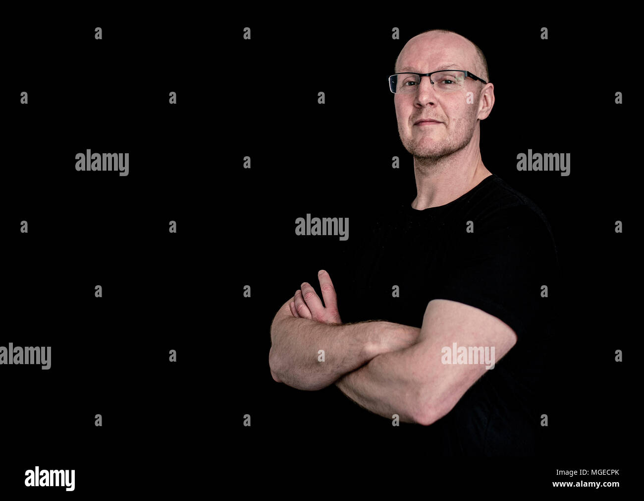 Middle aged blad man smiling in un t-shirt noir contre un fond de studio noir Banque D'Images