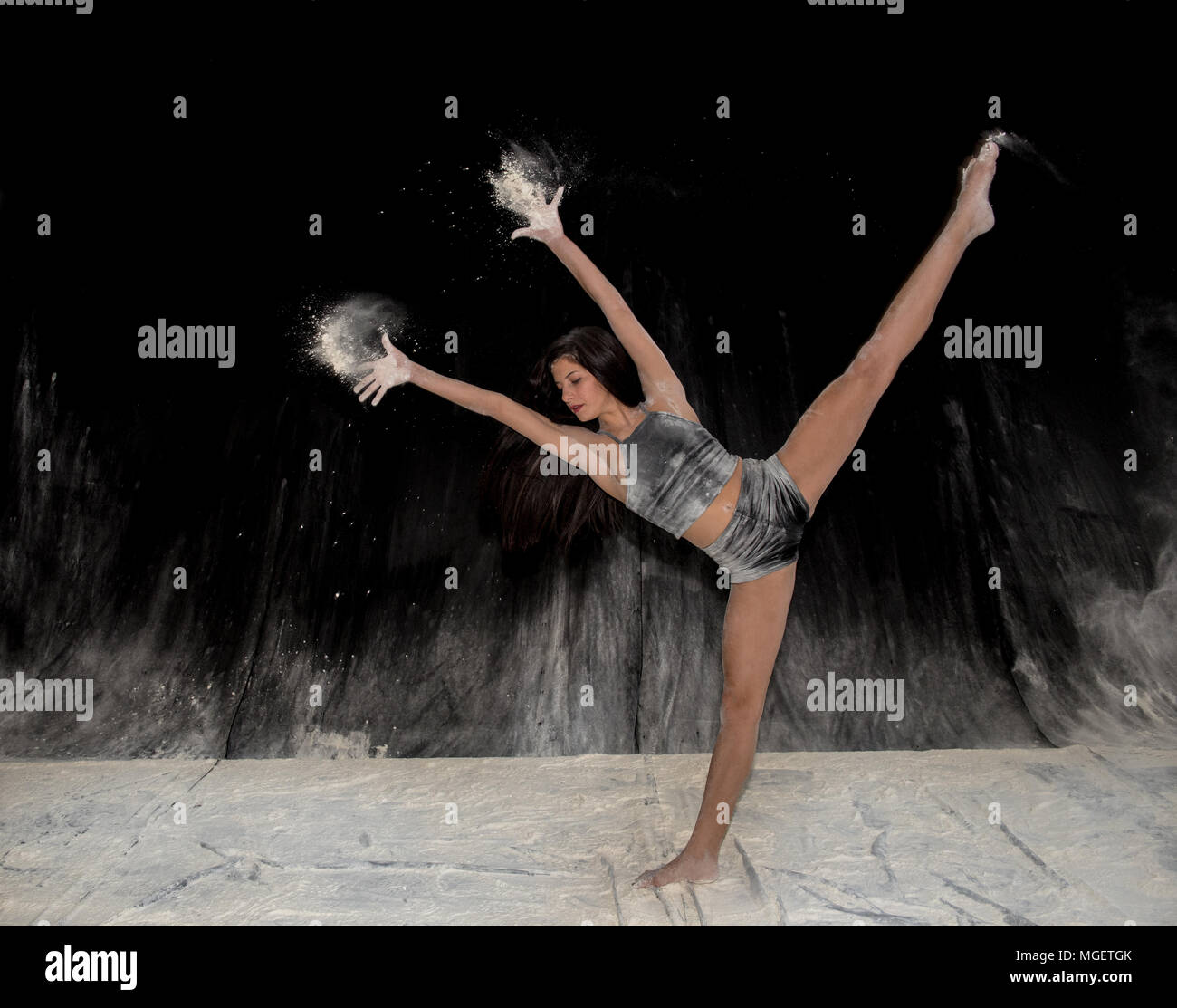 Belle adolescente expressive danse ballet contemporain sur scène avec un fond noir et la farine blanche Banque D'Images