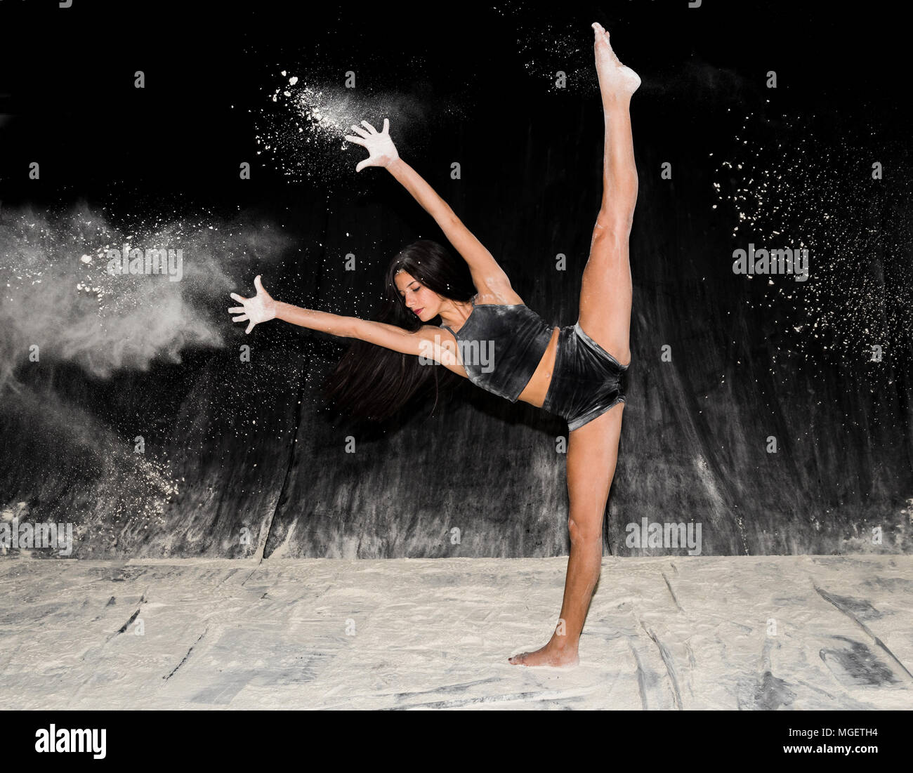 Belle adolescente expressive danse ballet contemporain sur scène avec un fond noir et la farine blanche Banque D'Images