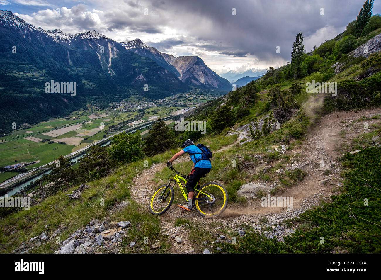Un homme monte un vtt haut au-dessus de la vallée, près des villes de Gampel et Jeizinen dans le Valais Suisse. Banque D'Images