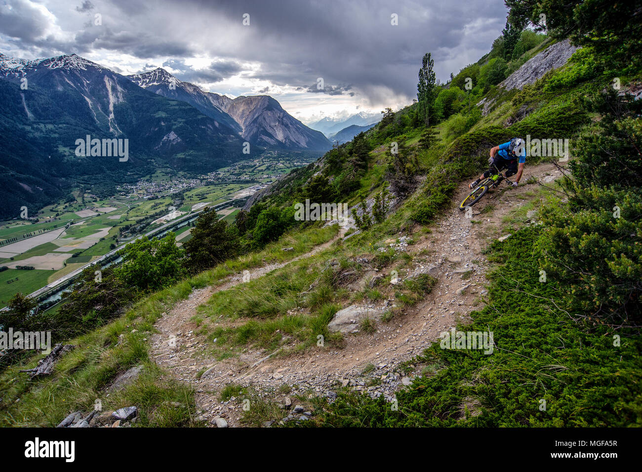 Un homme monte un vtt haut au-dessus de la vallée, près des villes de Gampel et Jeizinen dans le Valais Suisse. Banque D'Images