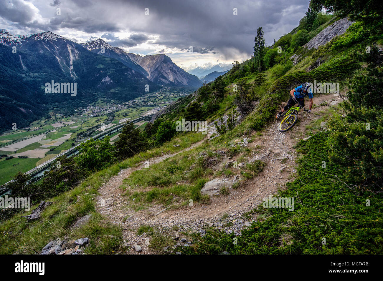 Un homme monte un vtt haut au-dessus de la vallée, près des villes de Gampel et Jeizinen dans le Valais Suisse. Banque D'Images