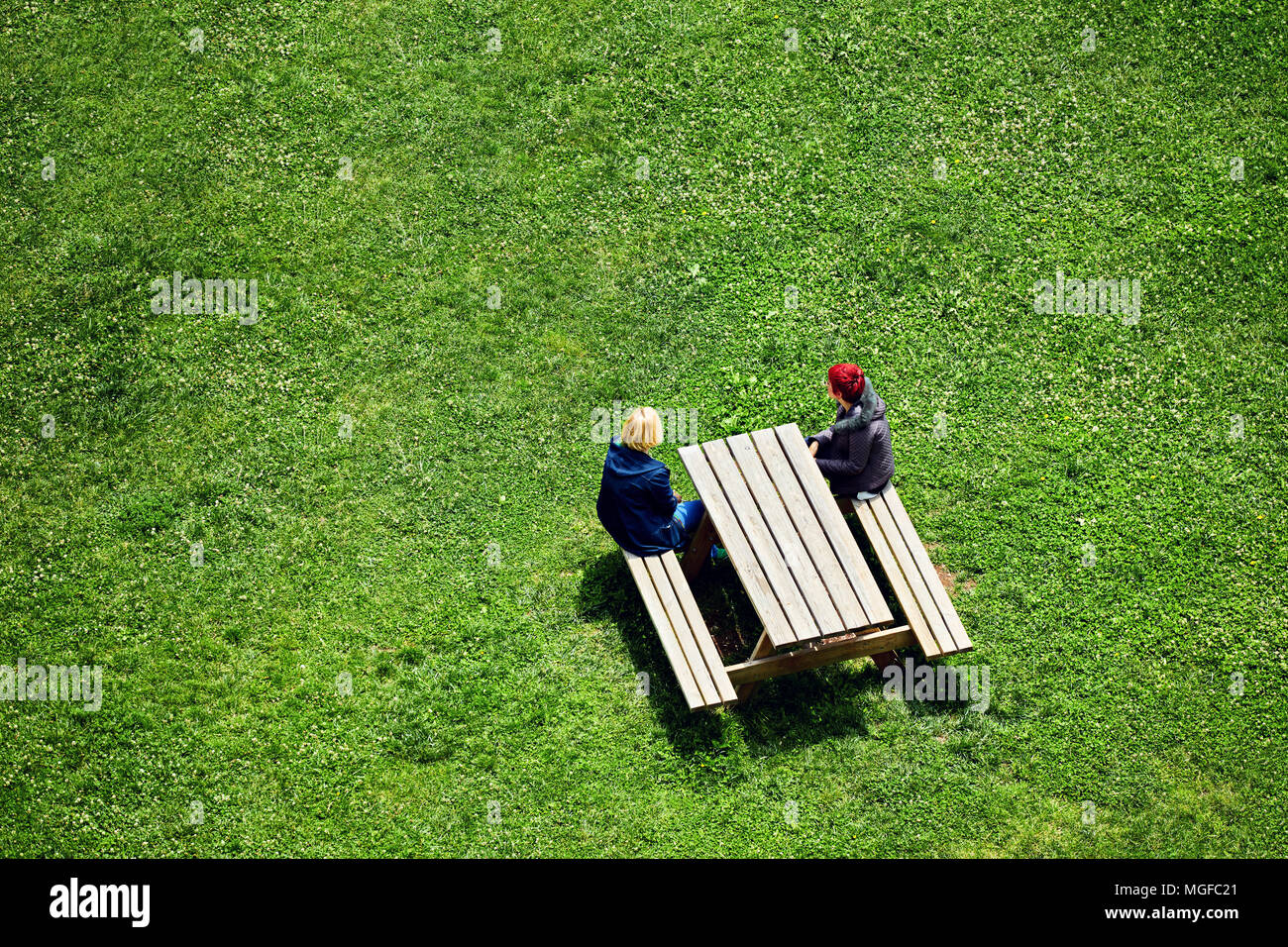 Deux femmes blanches d'âge moyen s'asseoir sur un banc et regarder l'espace vide dans le parc par une belle journée ensoleillée Banque D'Images
