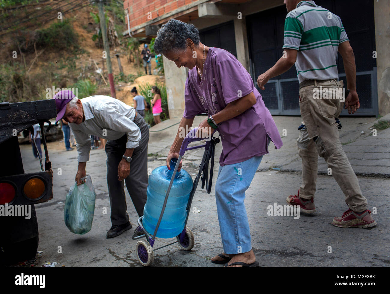 27 avril 2018, le Venezuela, Caracas : Une vieille femme portant une cruche d'eau sur un vieux panier à travers le Las Minas trimestre qu'elle en a l'air d'une source d'eau. L'approvisionnement en eau potable a été interrompu il y a 20 jours dans ce trimestre. De nombreuses personnes protestent dans plusieurs villes du pays. Les protestations ont été convoqués en raison de problèmes avec l'approvisionnement à travers les entreprises publiques. Photo : Manu Quintero/dpa Banque D'Images