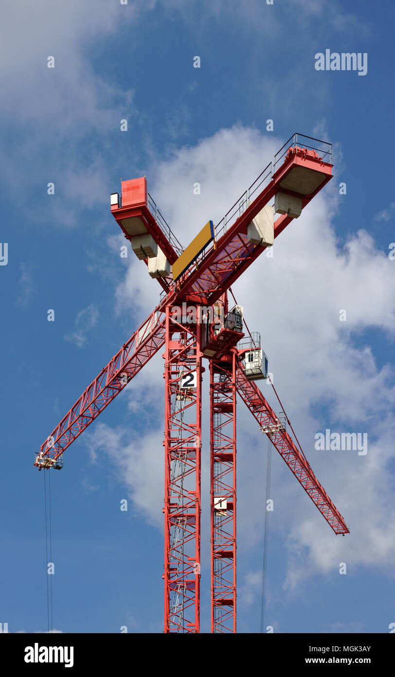 Deux grues rouges formant un grand X en face d'un ciel bleu avec des nuages blancs moelleux Banque D'Images