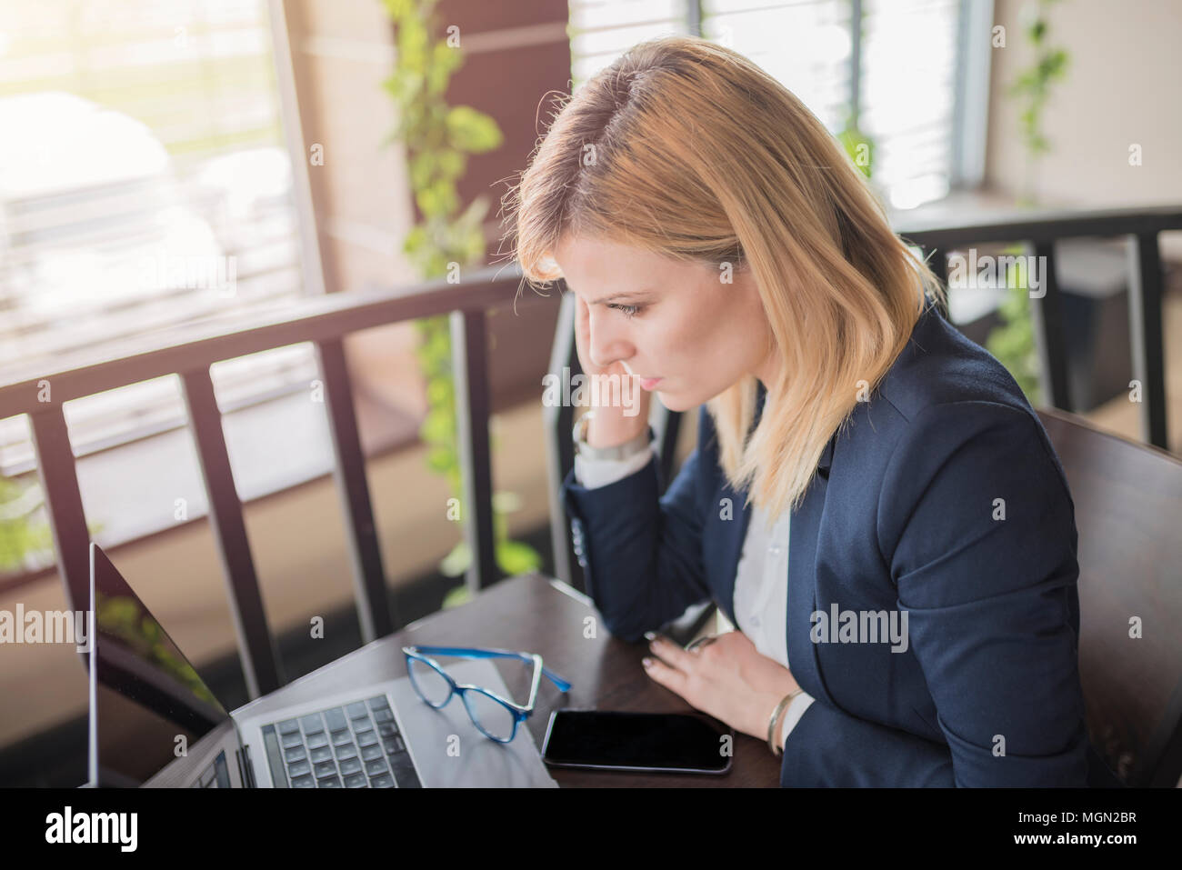 Jeune femme d'affaires nerveux en utilisant son ordinateur portable dans un restaurant. Jolie femme blonde travaille sur son ordinateur portable dans un café. Banque D'Images