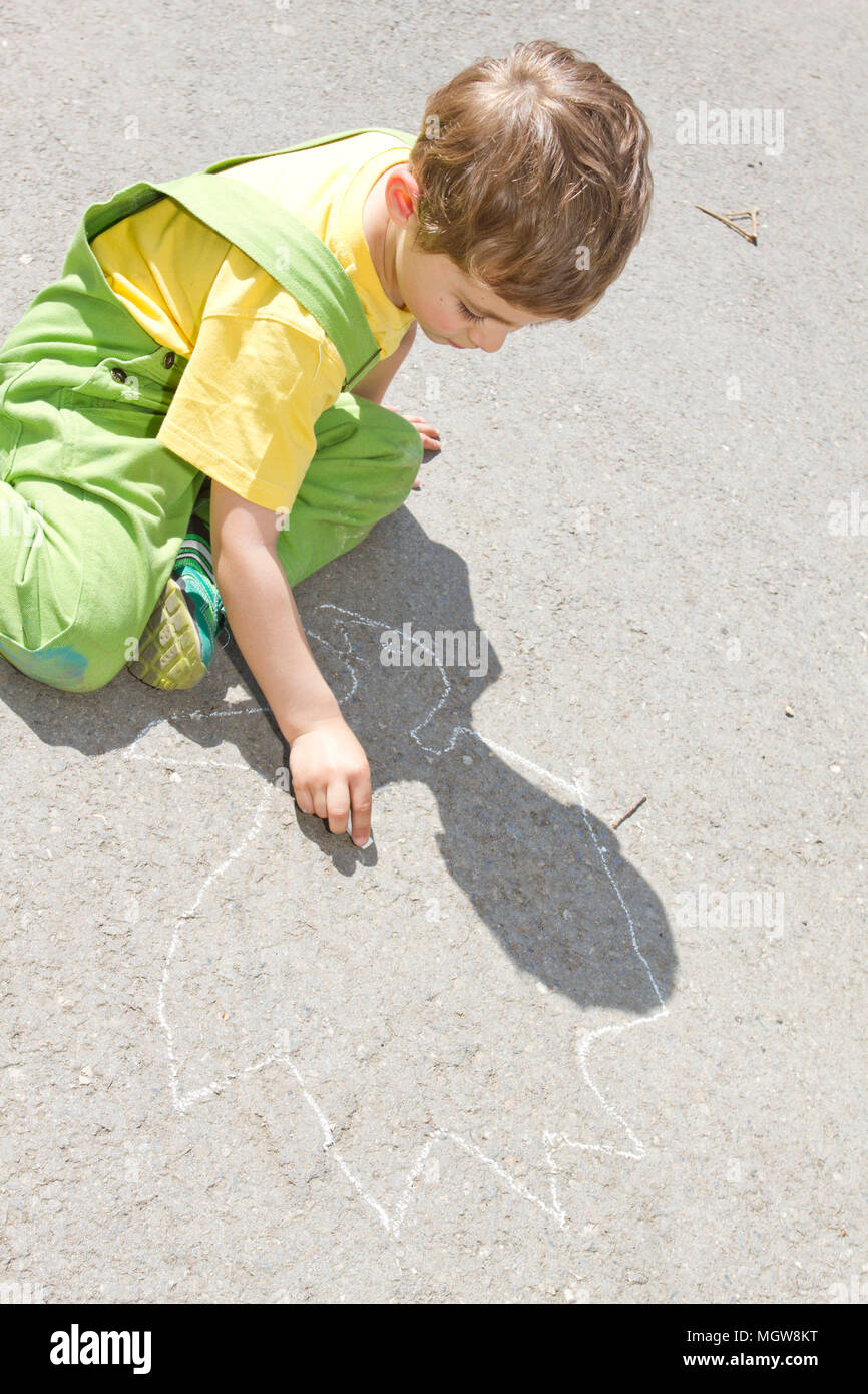 Cute boy nulles avec les craies colorées sur l'asphalte. L'activité d'été et des jeux créatifs pour les petits enfants. Enfant ensemble à s'amuser. L'école et locations de conc Banque D'Images