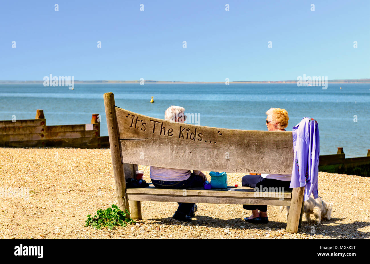 Couple de personnes âgées assis sur un banc au bord de la mer, Whitstable Kent Banque D'Images