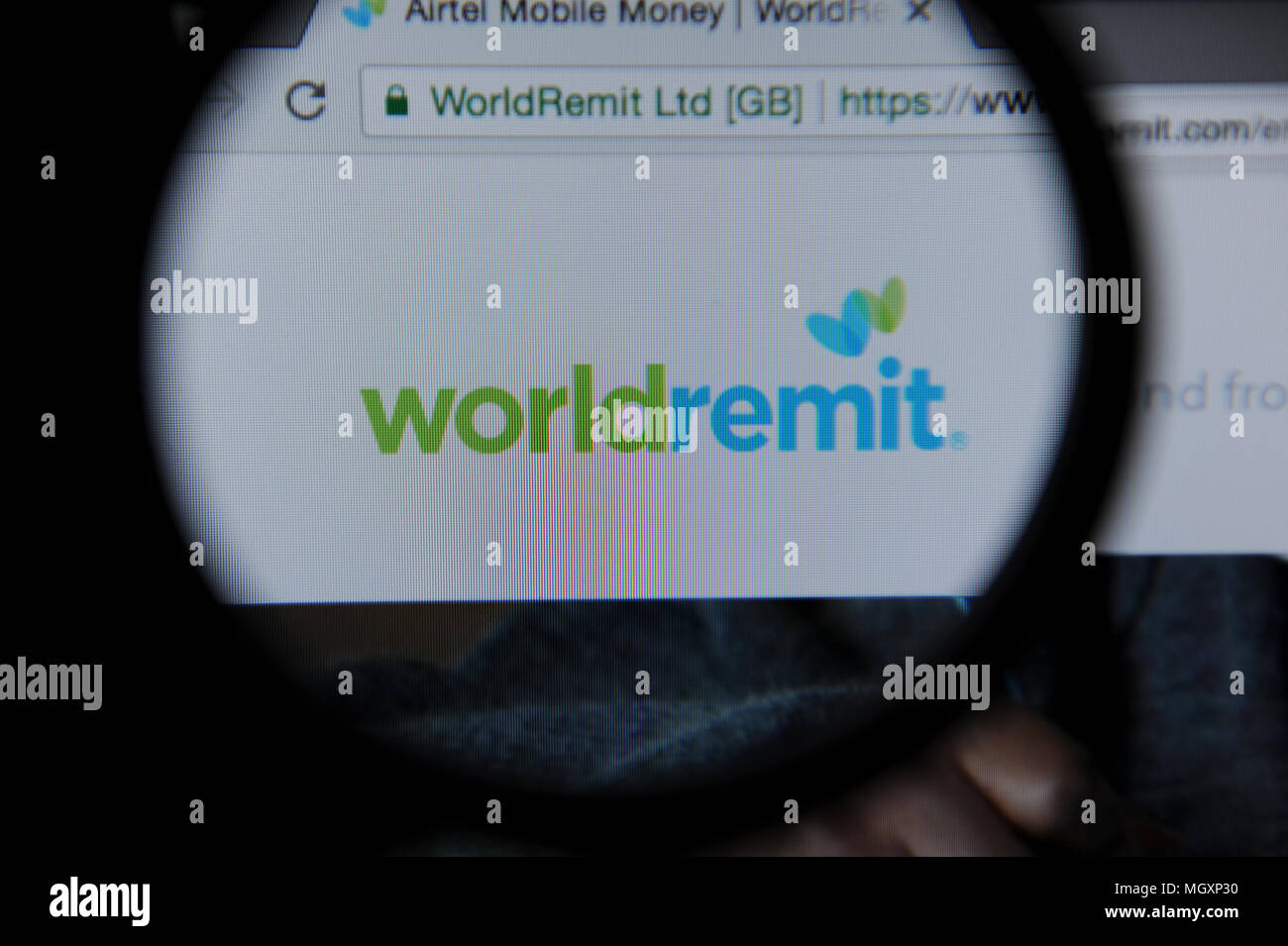 Logo vu WorldRemit à travers une loupe. WorldRemit est un service de transfert international fondé à Londres. Banque D'Images