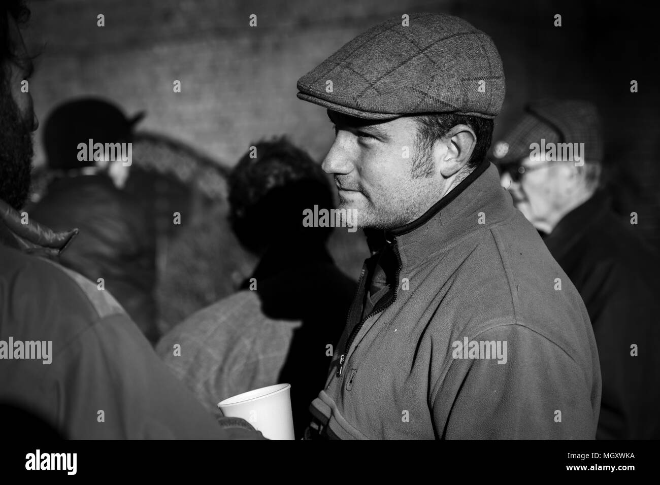 photo noir et blanc d'un homme à capuchon plat tenant une tasse blanche le matin ensoleillé Banque D'Images