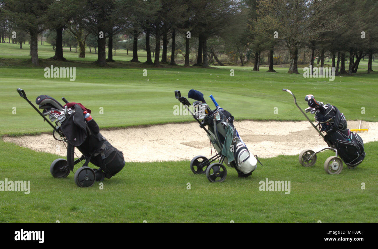 3 sacs de golf à gauche une ligne à côté d'un bunker de sable sur l'allée d'un terrain de golf. Banque D'Images