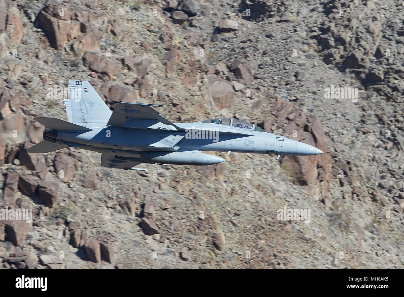 Vue de profil d'un United States Navy F/A-18F Super Hornet chasseur à réaction volant à basse altitude par Rainbow Canyon en Californie, aux États-Unis. Banque D'Images