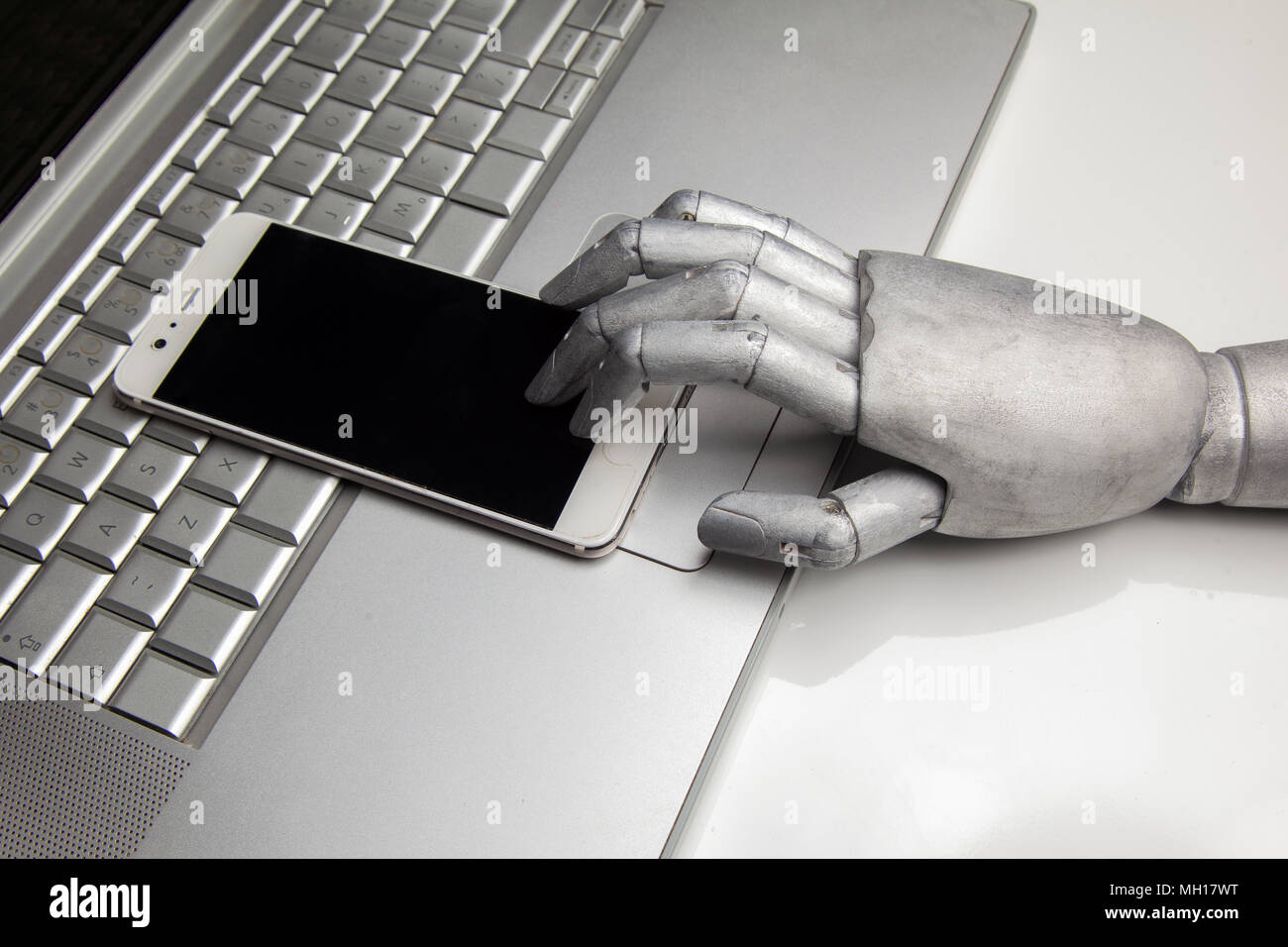 Smartphone brillant avec robot part le toucher par le doigt sur l'ordinateur portable Banque D'Images