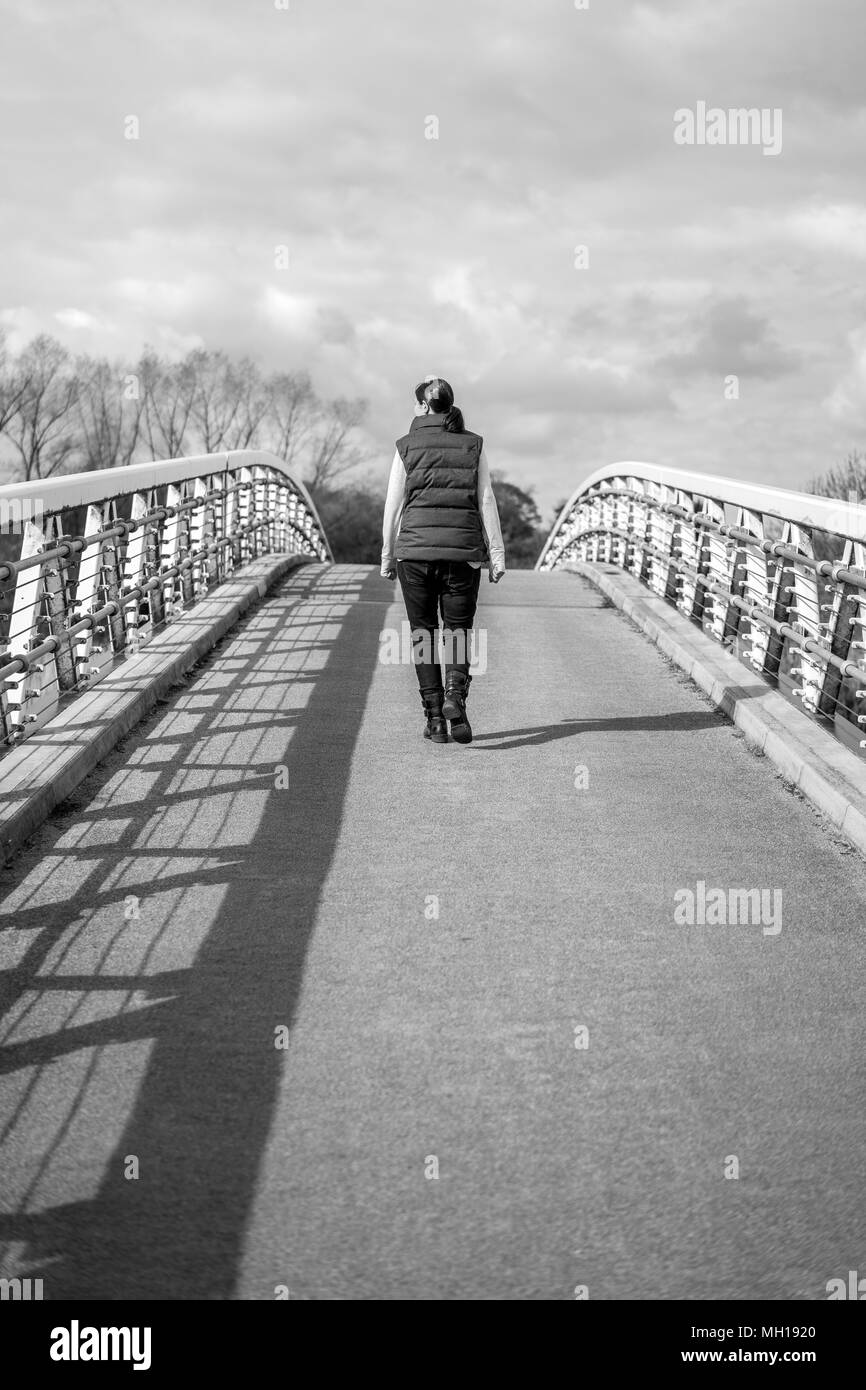 Voir l'unique de dame de derrière la marche sur le pont vide en noir et blanc Banque D'Images
