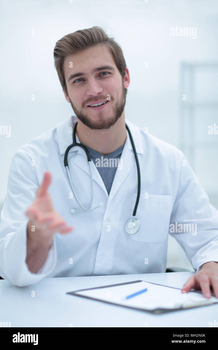 Beau médecin en blouse blanche offre sa main Banque D'Images